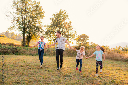 Happy family playing together outside  father and children with holding hands runing together in the summer park.