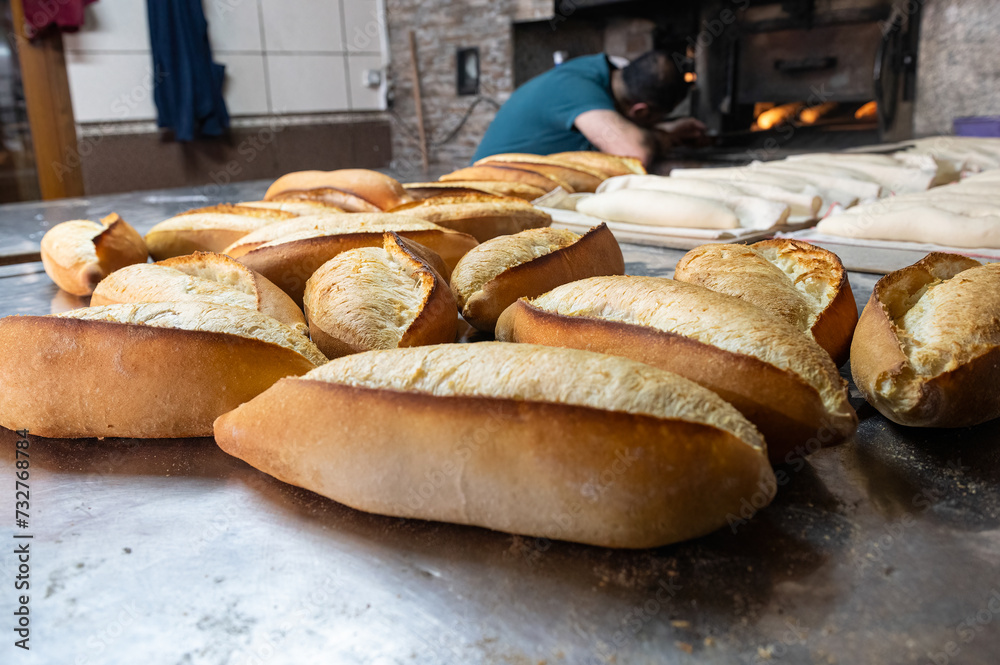 When the baker takes the baked bread out of the oven, the bread inside the oven is visible.