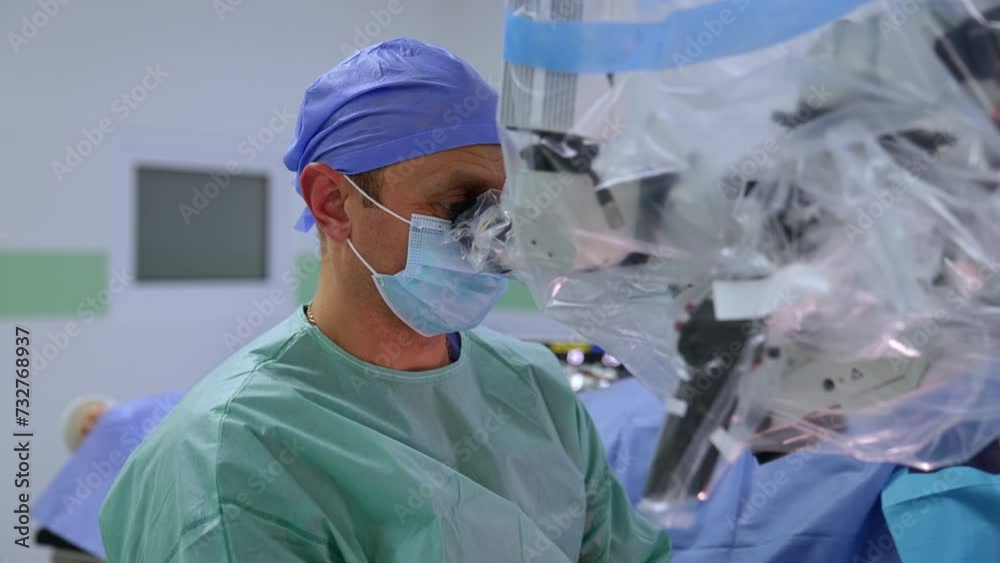 Calm confident surgeon looks attentively at microscope. Portrait of a neurosurgeon performing microsurgery. Calm confident surgeon looks attentively at microscope. Portrait of a neurosurgeon performing microsurgery.