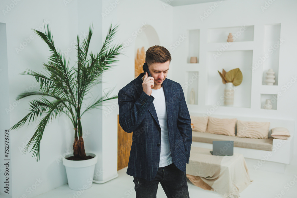 Photo of happy handsome man in classic jacket, talking on mobile phone and smiling. Remote work at home Photo of happy handsome man in classic jacket, talking on mobile phone and smiling. Remote work at home