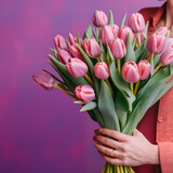 Creative arrangement of tulips on a purple background with happy Mother's Day text. Flat lay. 
Womend hands holding tulips. 
Spring concept.