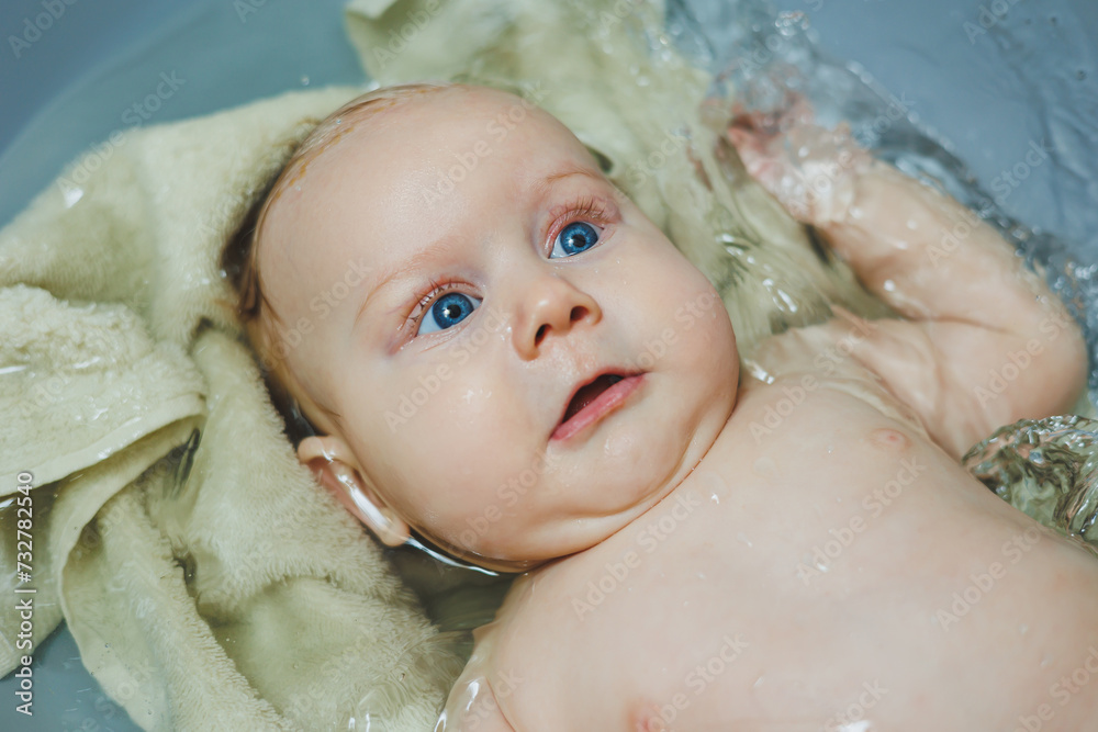 Photo of a 5-month-old baby lying in a baby bath. A four-month-old baby is bathing in water. Caring for a newborn baby Photo of a 5-month-old baby lying in a baby bath. A four-month-old baby is bathing in water. Caring for a newborn baby
