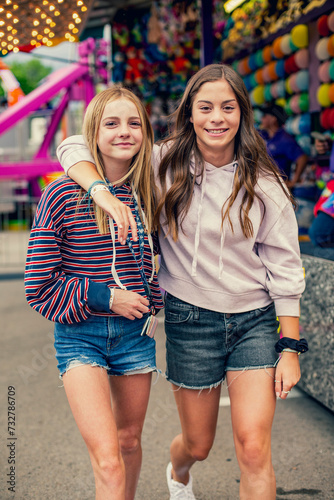 Foto Candid photo of two cute and smiling teenage girls having fun at an outdoor carnival or theme park