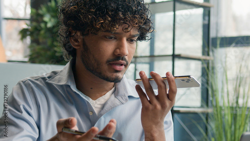 Annoyed Indian businessman stressful guy arguing talk phone quarrel business discussion in office Arabian man shout solve conflict male dissatisfied employee talking loudspeaker record voice message