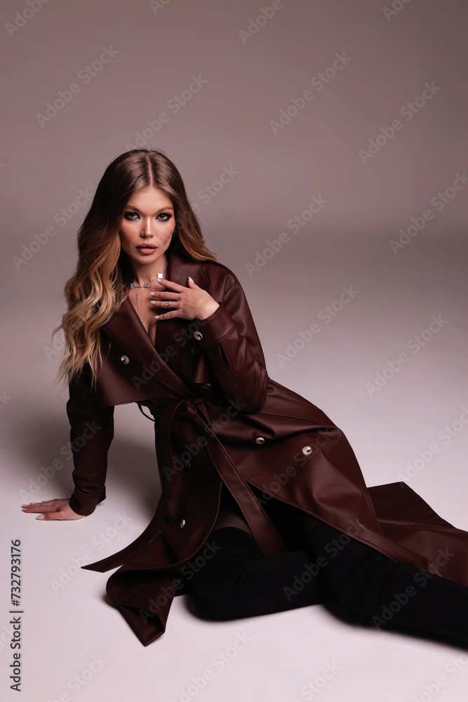 beautiful woman with blond hair in luxurious leather brown coat posing in studio beautiful woman with blond hair in luxurious leather brown coat posing in studio