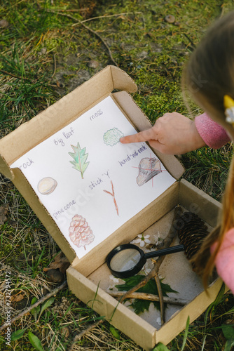 Scavenger hunt for kid in the park. Girl learning about environment. Natural education activity for World Earth day. Exploring in spring.