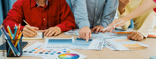 A cropped image of professional interior designer discuss the color material with her colleagues by comparing with color swatches and color palette document. Creative design concept. Variegated.