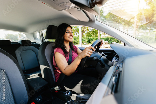 Young adult happy indian woman driving a car in the city. Rental car service concept