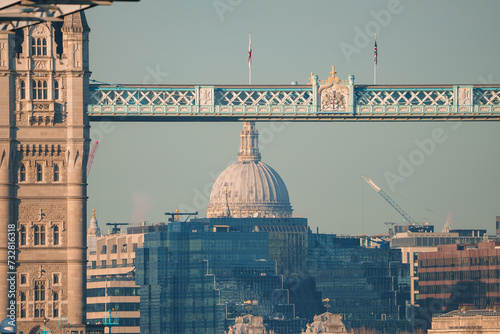 Scenic London view featuring the Tower Bridge's Victorian Gothic architecture and St. Paul's Cathedral's iconic dome, bathed in warm light, with ongoing city development. photo