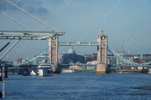 A serene daytime view of London's Tower Bridge with its Gothic architecture and the River Thames below. St. Paul's Cathedral graces the background amidst a clear blue sky. photo