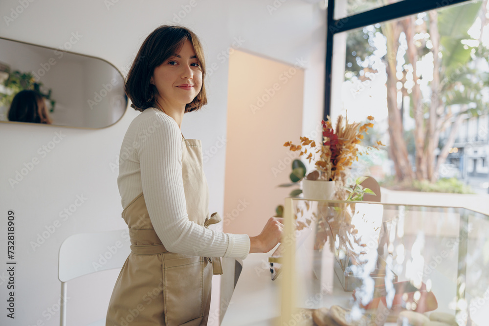 Portrait of a happy female barista standing behind the counter in a coffee shop Portrait of a happy female barista standing behind the counter in a coffee shop