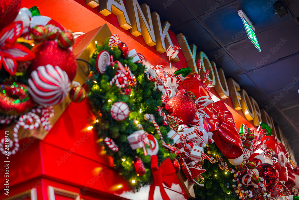 A vibrant Christmas display in London with a THANK YOU sign, red and green garlands, oversized candy canes, and shiny baubles, creating a warm, festive atmosphere.