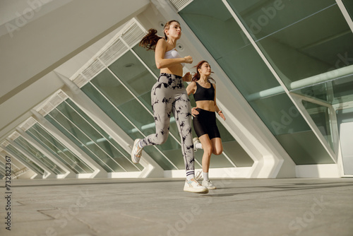 Two athletic women in sportswear is jogging around the city in early morning. Reaching the goal