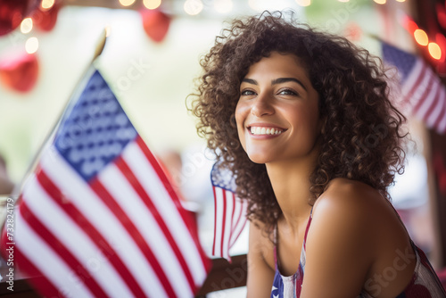 pretty Hispanic woman preparing for a July 4th party or citizenship celebration with US flags in soft focus in the background