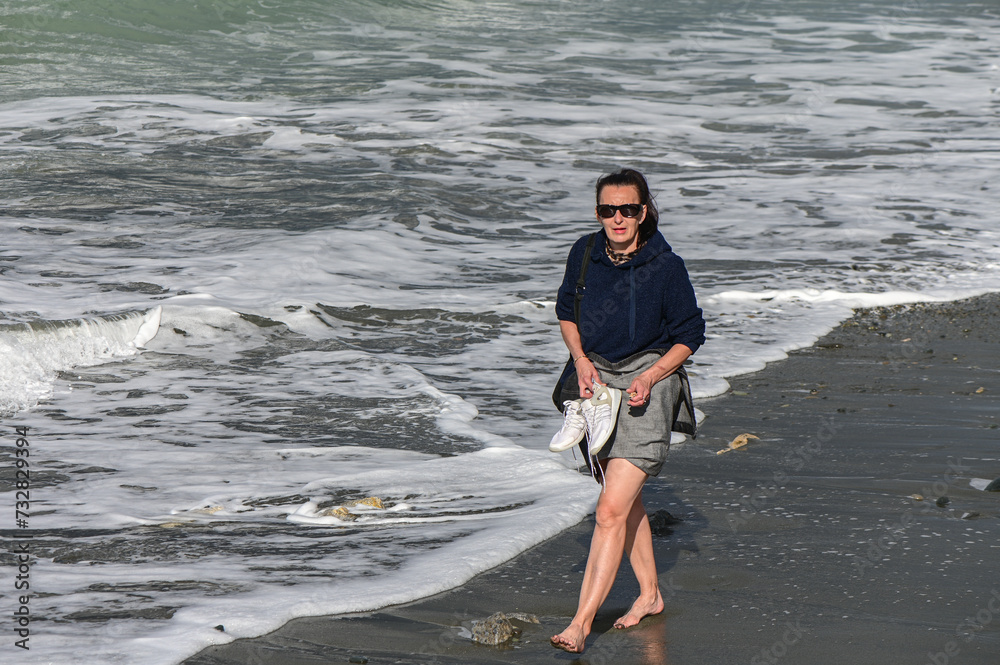 woman walks barefoot along the Mediterranean Sea in Cyprus in winter 2023 10