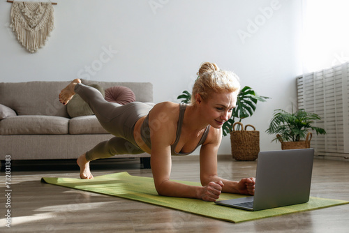 Sporty adult woman teaching calisthenics in an online class. Athletic middle aged female live streaming fitness lessons. Background, copy space, close up. photo