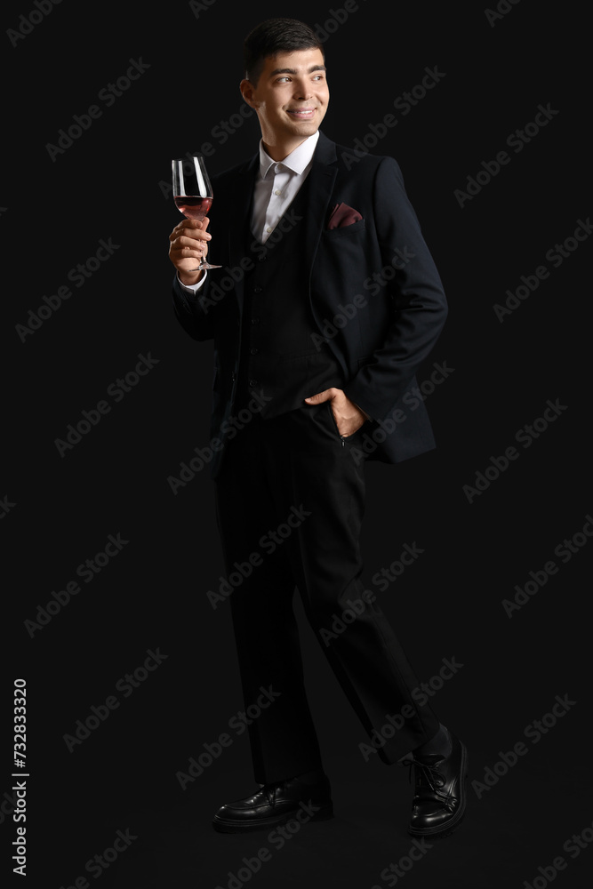 Obraz premium Young sommelier with glass of pink wine on black background
