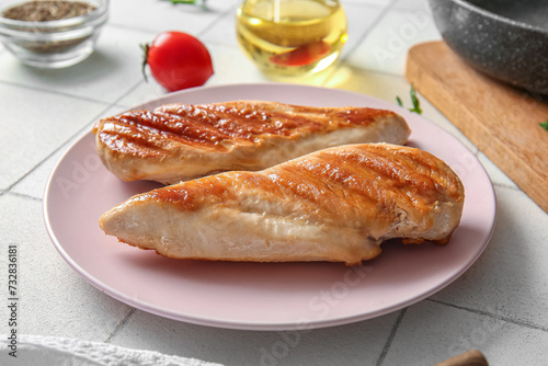 Plate with tasty grilled chicken breast on white tile background