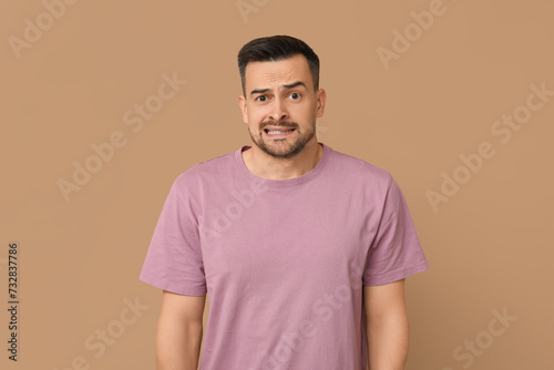 Handsome ashamed young man on brown background