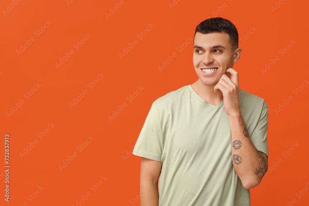Handsome ashamed young man on orange background Handsome ashamed young man on orange background