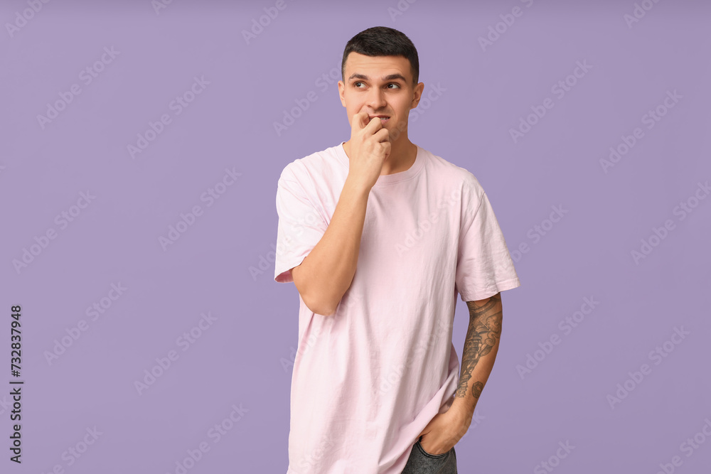 Handsome ashamed young man on lilac background