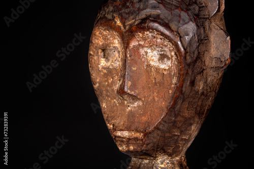 An African male figure portrait carved in wood isolated on black. Traditional African art with balanced shapes and volumes and beautiful black patina and kaolin pigments. photo