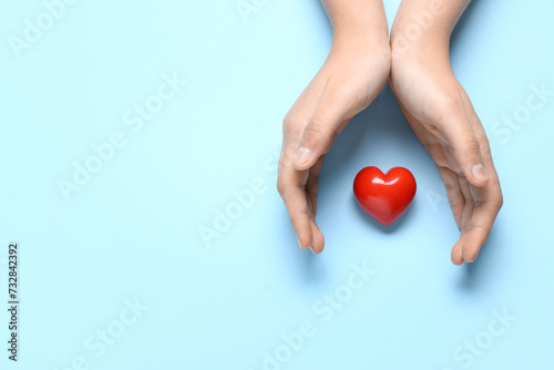 Female hands with red heart on blue background