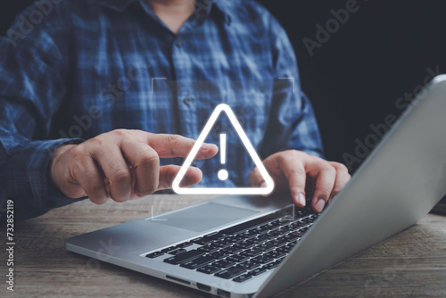 Businessman or it staff , programmer, developer using computer laptop with triangle caution warning sign for notification error and maintenance concept.