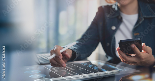 Businesswoman working on laptop, using mobile phone at modern office, analyzing business document with financial graph, market report on digital tablet, business data analysis concept