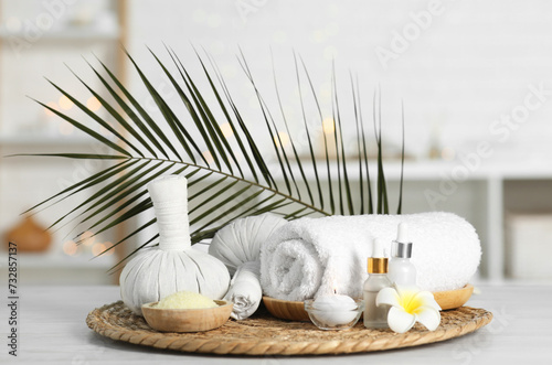 Composition with different spa products and plumeria flower on white table indoors