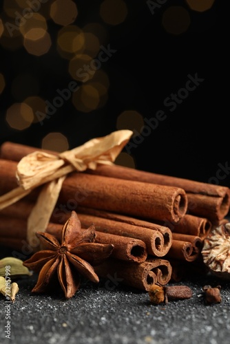 Different aromatic spices on grey textured table against black background, closeup