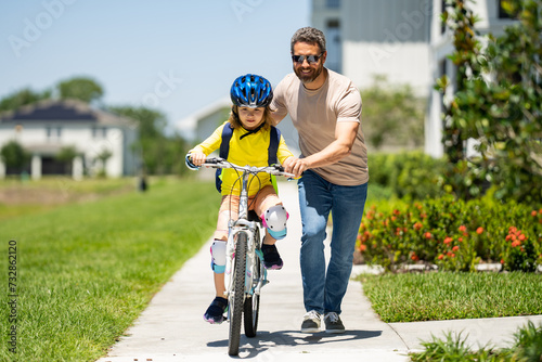 Fathers day. Father and son riding a bike on the road at the fathers day. Concept of friendly family. Parents and children being friends. Father and son riding a bike outdoor. Child first bike.