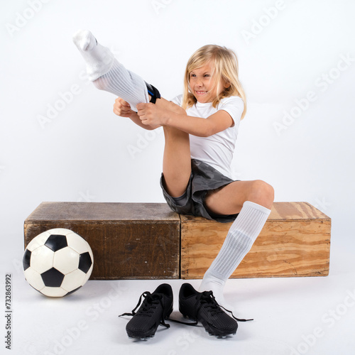 Young soccer player struggling to put on soccer uniform socks photo