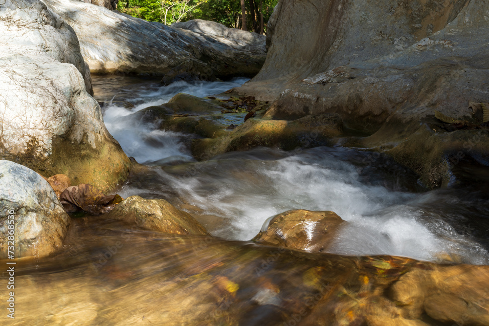 summer waterfall stream with rocks on nature clear flow motion water from trees in jungle or fresh natural forest at Phalad Waterfall in rainforest Lan sang national park for landscape background