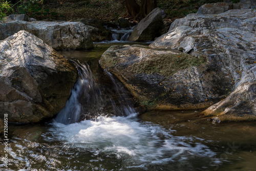 summer waterfall stream with rocks on nature clear flow motion water from trees in jungle or fresh natural forest at Phalad Waterfall in rainforest Lan sang national park for landscape background