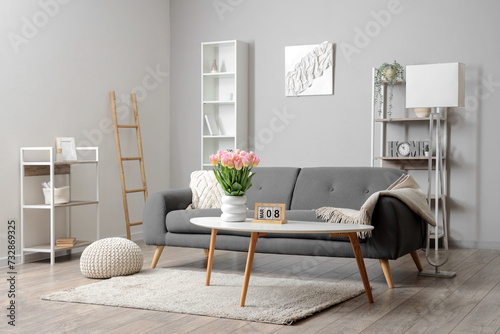 Interior of living room with sofa and tulips in vase for International Women's Day #732869325