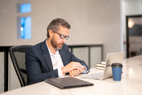 Business worker with laptop at office. Employee remote working in modern office. Business man on online meeting. Hispanic business man working online. Mature business man using laptop at workplace.