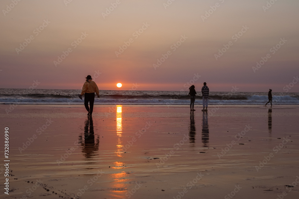 A peaceful moment on the coast, families walking during a sunset seascape
