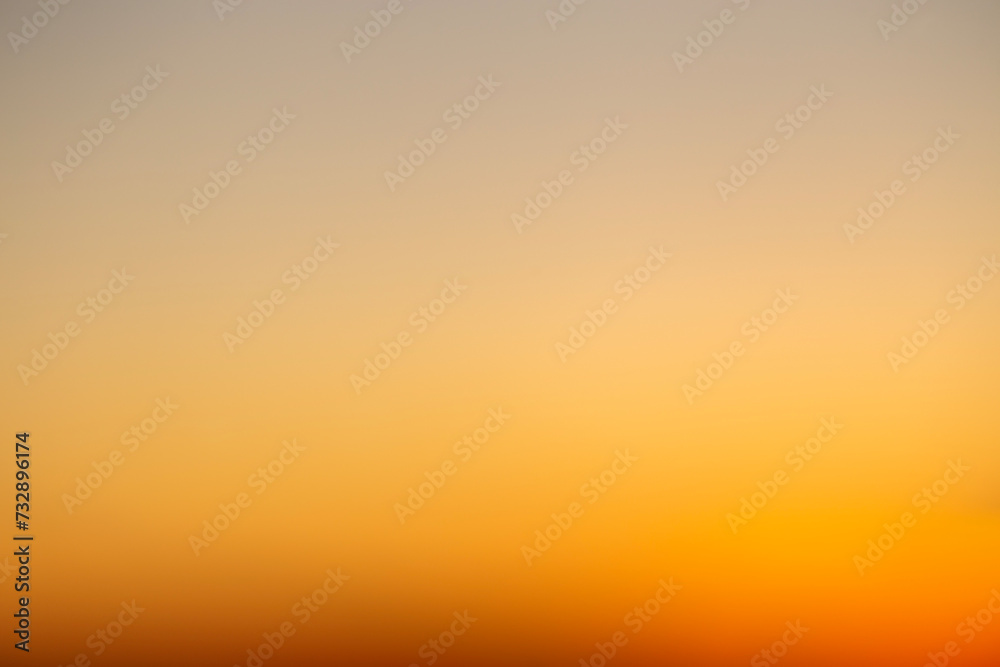 Abstract defocused shot of the sky during sunset hours casting a deep orange light