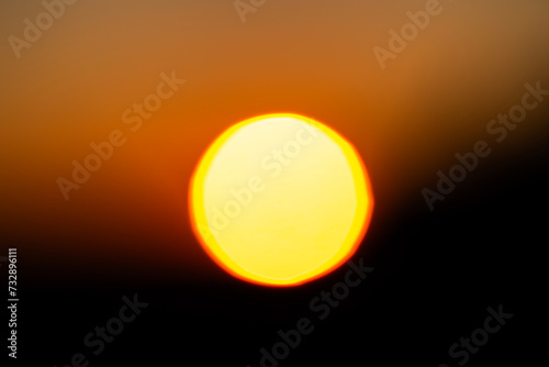 defocused blurred abstract shot of the sun setting behind a mountain