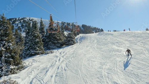Chair-lift at ski resort against snowcapped forest tree and mountain peaks covered in snow landscape in luxury winter alpine resort. Winter leisure sports, recreation and travel.