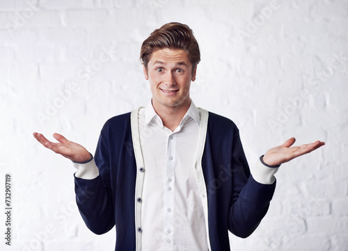Confused, shrug and portrait of man with doubt on wall background for choice, option and decision. Facial expression, thinking and isolated person with unsure, question and wonder reaction in studio photo