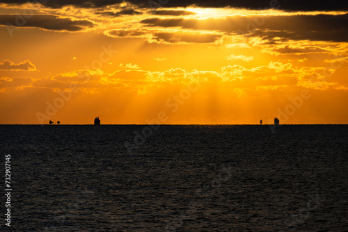 雲間の太陽からの光と水平線と沖の船のシルエット20240108-1