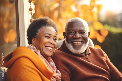 A black grandfather and black grand mother smiling and happy in a bright livingroom with fall deco