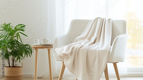 A white blanket draped over a single chair in a white living room used for mockup, brightly lit, 