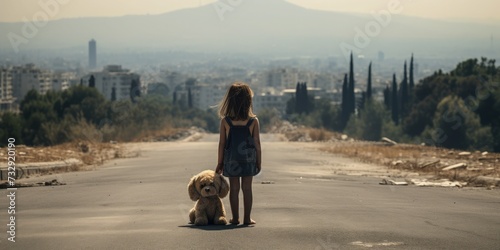 A young girl standing in the middle of the road holding a teddy bear. © Dara