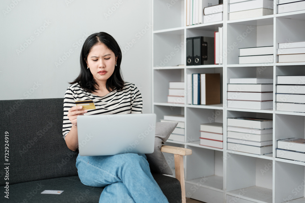 Asian woman holding credit card and using laptop. woman working at home. Online shopping, e-commerce, internet banking, spending money, working from home concept. Asian woman holding credit card and using laptop. woman working at home. Online shopping, e-commerce, internet banking, spending money, working from home concept.