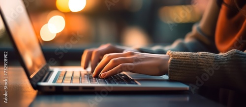 Close up of woman's hands typing on laptop keyboard on blurred background