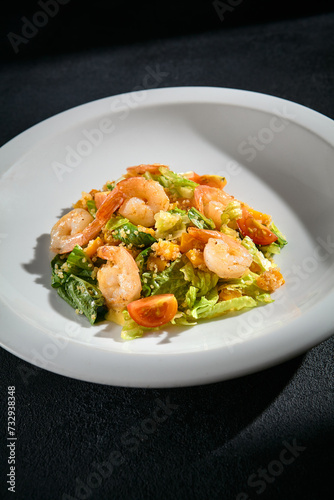 Shrimp salad with quinoa and mixed greens closeup, garnished with cherry tomatoes and a light dressing