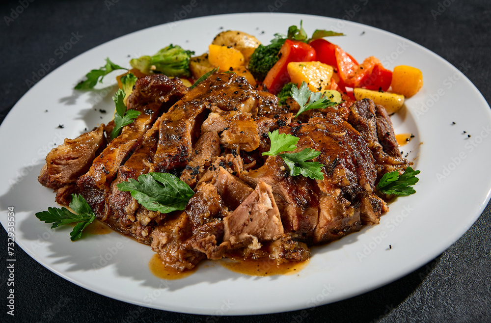 Close-up of beef brisket with roasted vegetables on a white plate